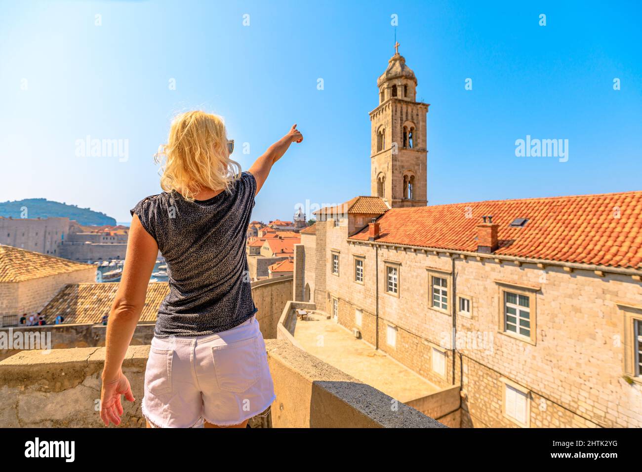 Woman on top of the Dubrovnik walls in Croatia of Dalmatia. Looking the Bell tower of the Dominican monastery and church of 1225. Aerial view on the Stock Photo
