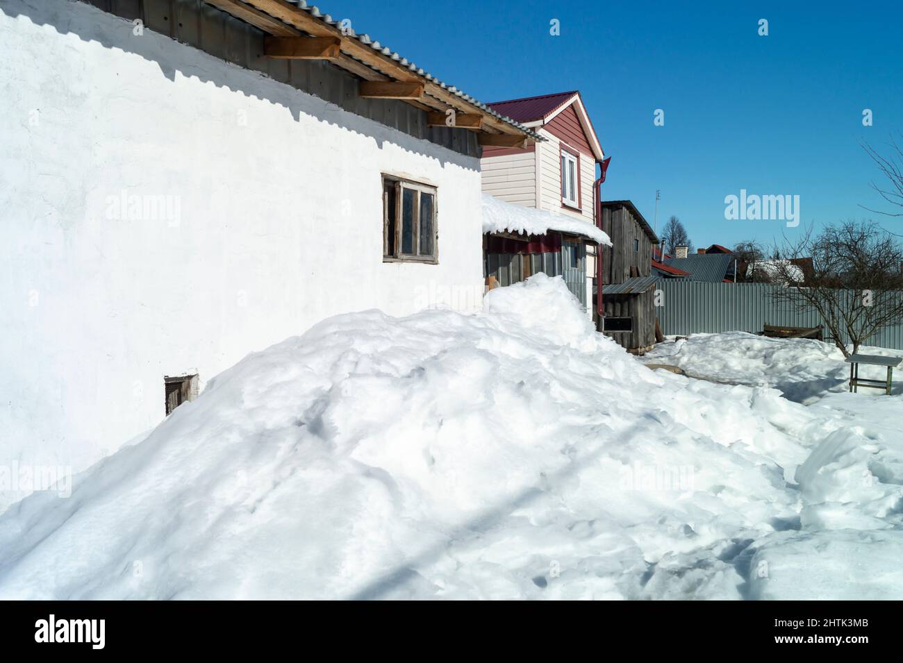 Snow drifts in the village outdoors. Landscape on a sunny day against a blue sky Stock Photo