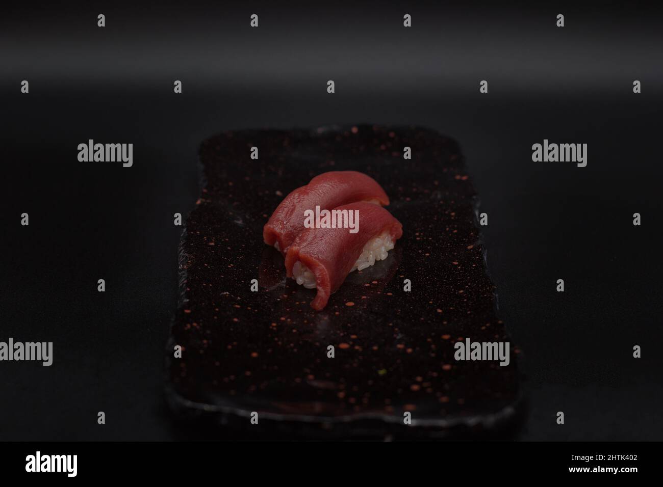 Two units of fresh and traditional red tuna nigiris served in black plate on a black background by a Japanese restaurant chef. Stock Photo