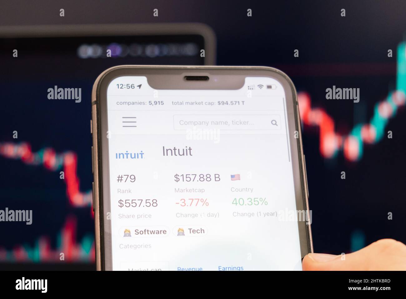 Intuit stock price on the screen of cell phone in mans hand with changing stock market exchange with trading candlestick graph analysis, February 2022, San Francisco, USA Stock Photo