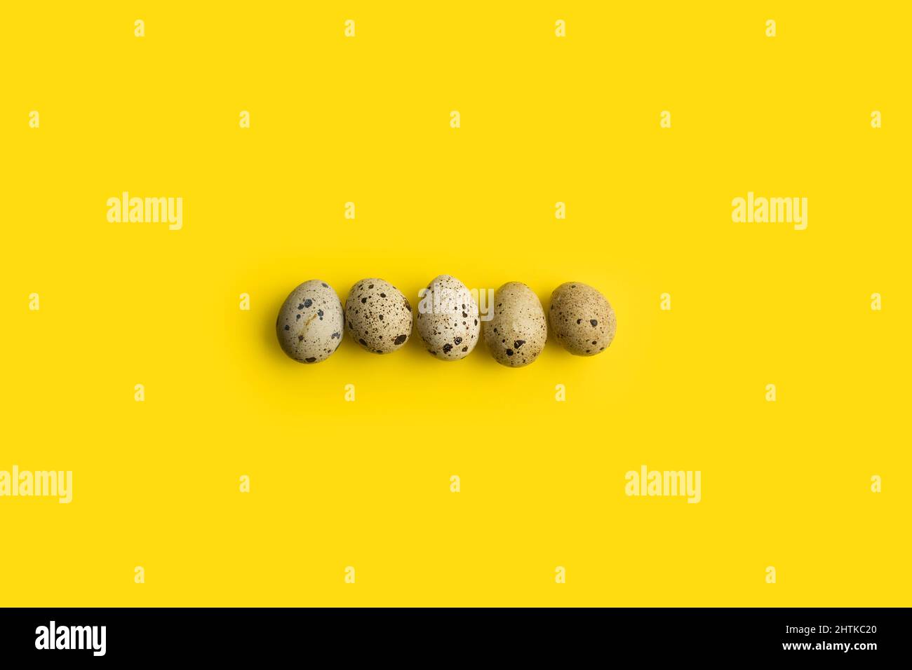 Five quail eggs on a yellow background with copy space Stock Photo