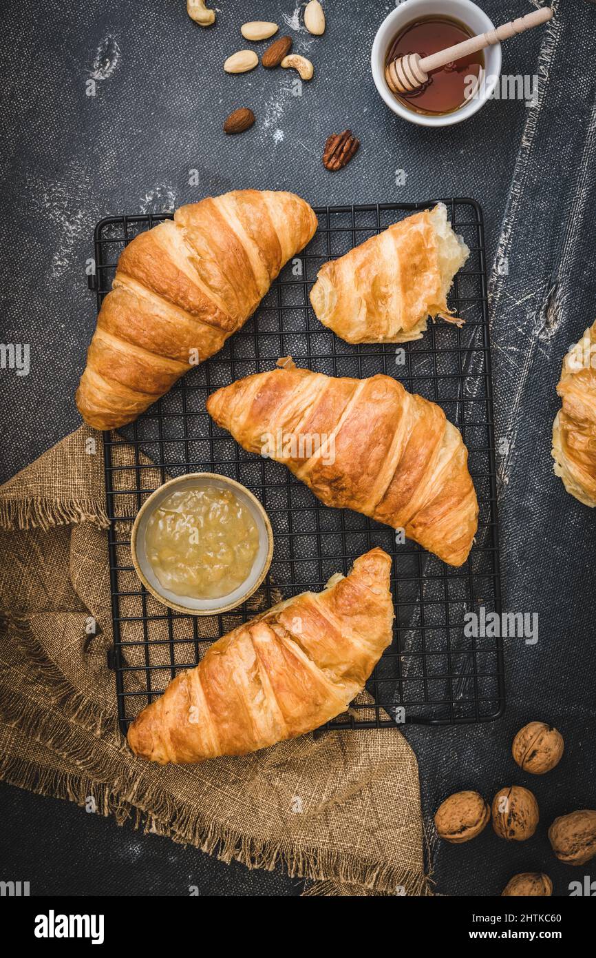 Breakfast scene with croissants, honey, jam and coffee and nuts, black