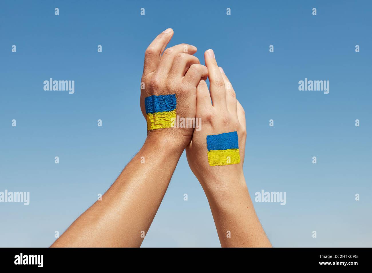 Female and male hands painted in Ukraine flag colors holding. Stop the war Stock Photo