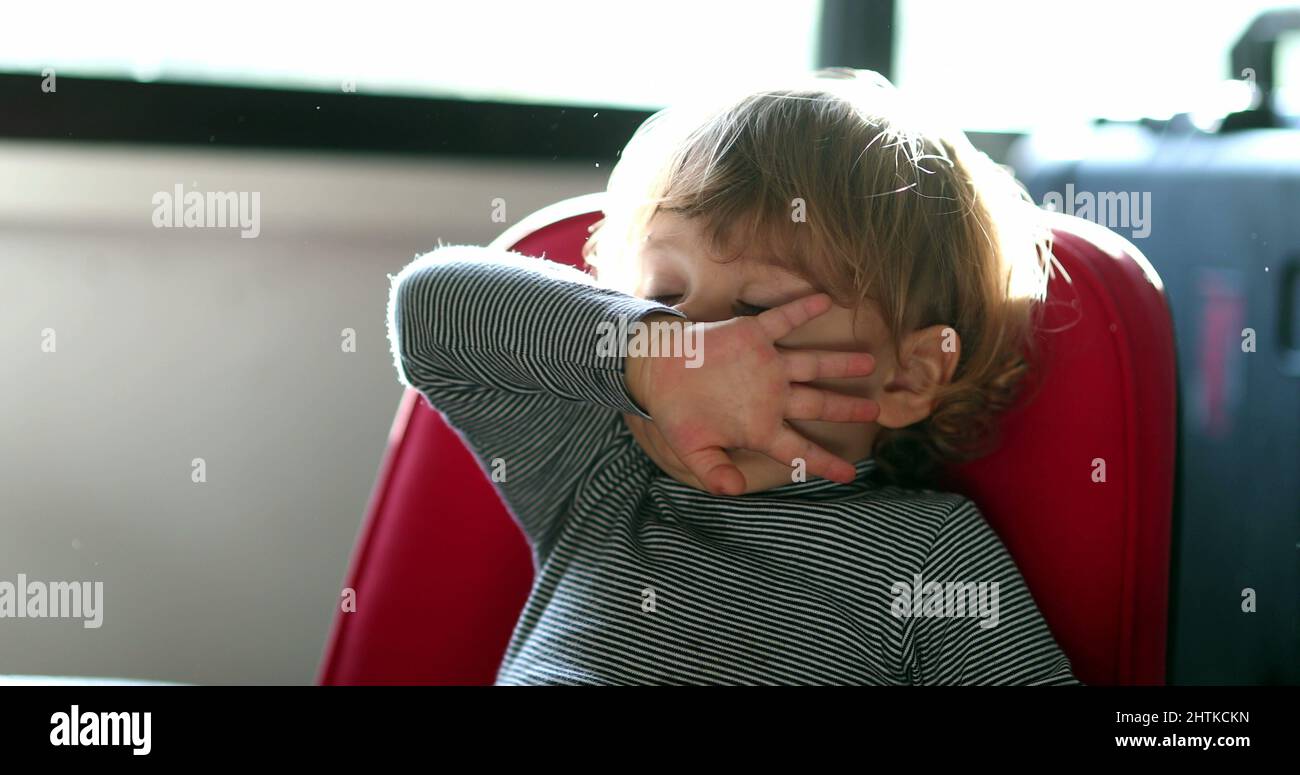 Allergic toddler wiping nose with sleeve and hand. Child wipes running