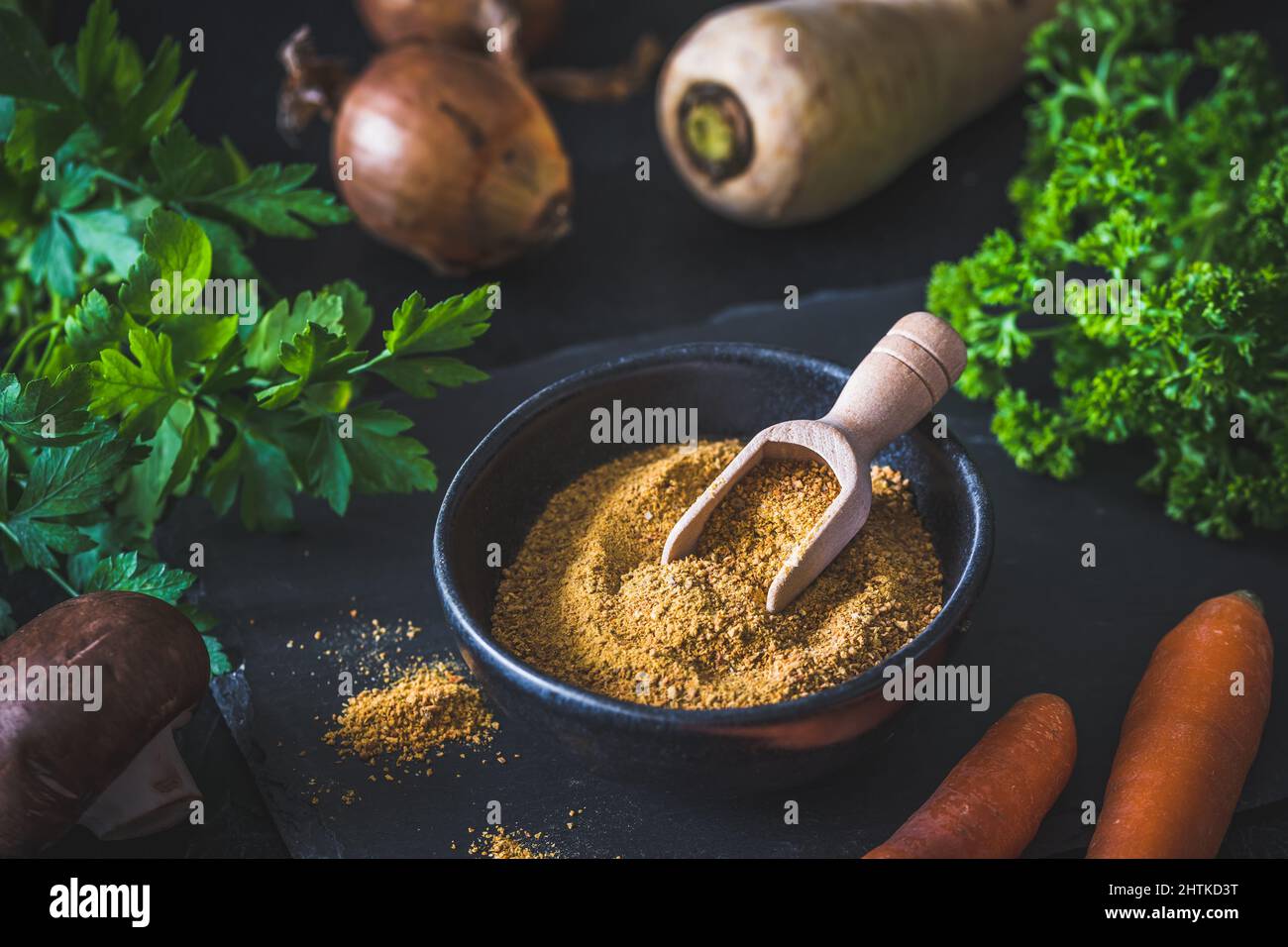 Homemade vegetable broth powder in a black bowl, organic vegetable stock, with raw vegetables on