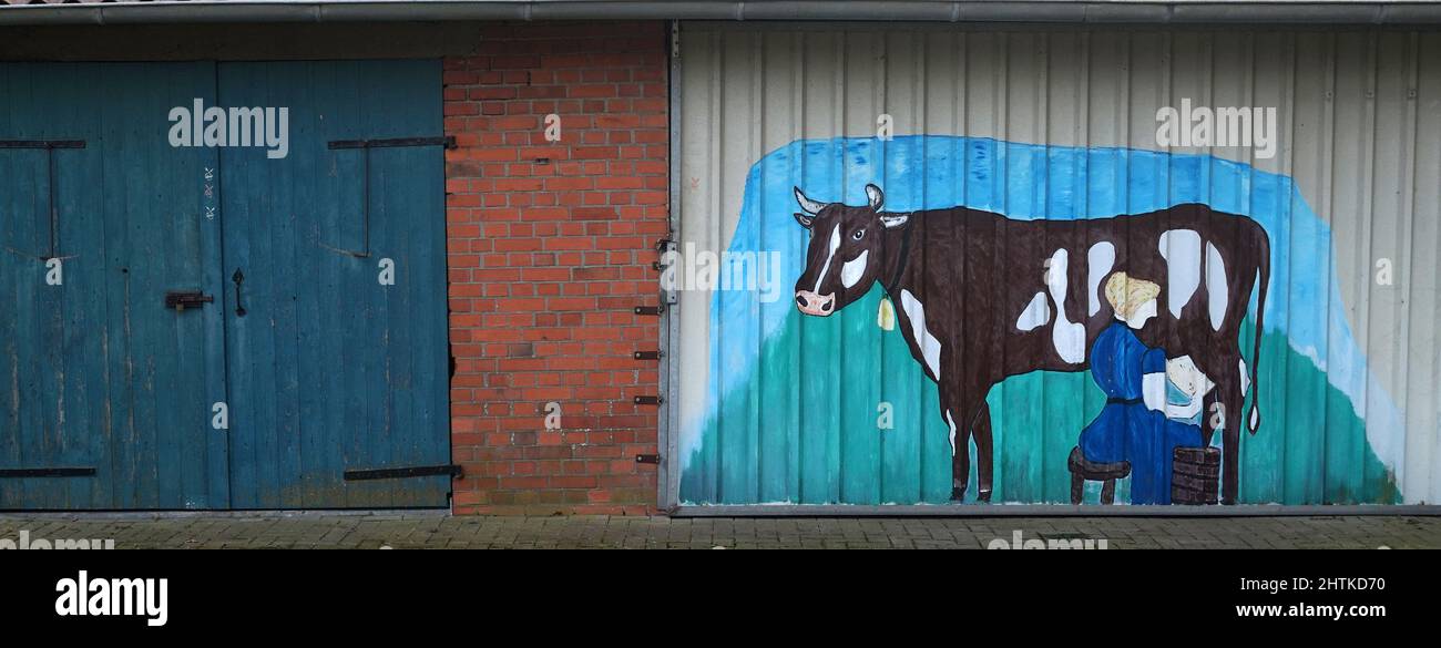 Laar, Germany - March 1 2022. Street art. Two stable doors. The second door has painting of a farmer woman milking a cow Stock Photo