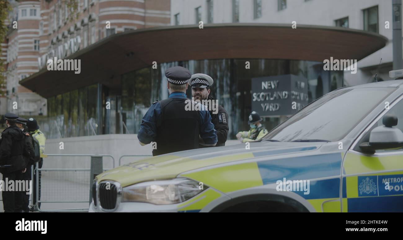 London, UK - 11 20 2021:  Two police officers on duty talking outside New Scotland Yard on Victoria Embankment, for an Insulate Britain protest. Stock Photo