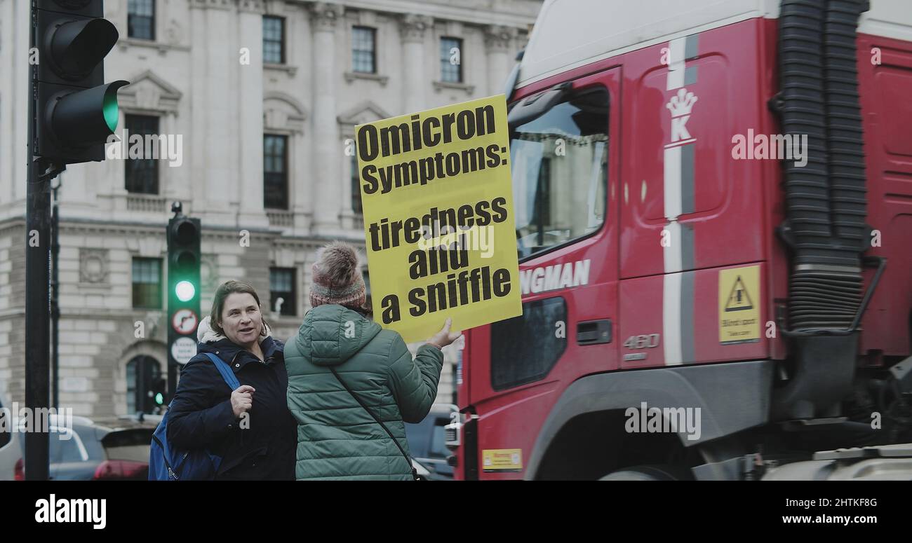 London, UK - 12 13 2021:  A woman holding a sign ‘Omicron Symptoms:  tiredness and a sniffle.’ on Westminster Bridge Road, at a freedom rally. Stock Photo