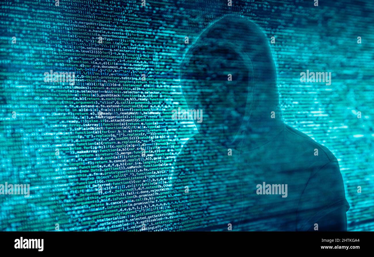 The silhouette of a hacker in front of program code Stock Photo