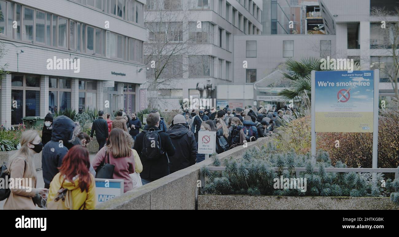 London, UK - 12 13 2021:  A long queue of people waiting in line for their booster vaccination, outside St Thomas’ Hospital Vaccination Centre. Stock Photo