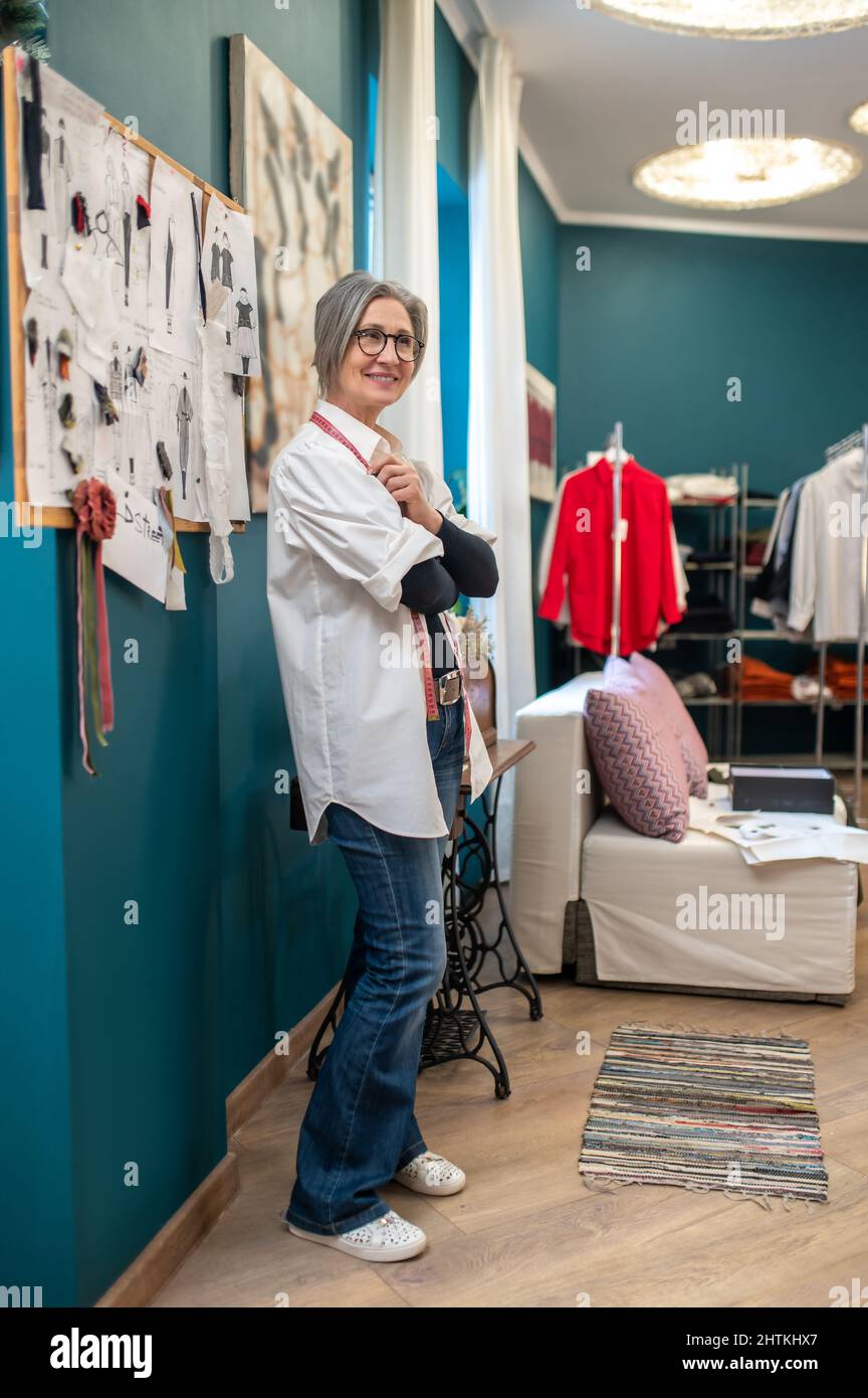 Woman standing sideways to camera in cozy sewing workshop Stock Photo
