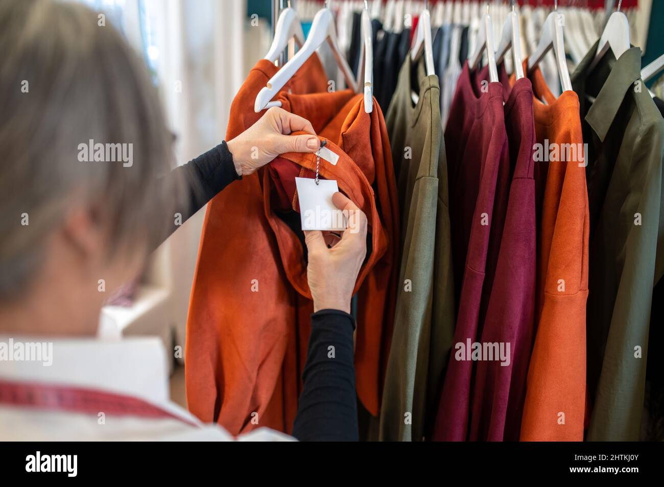 Womans hands touching tag on suit on stand Stock Photo