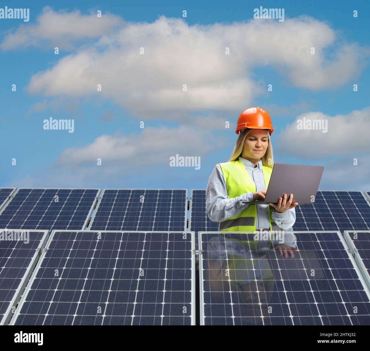 Female engineer with a laptop computer standing between solar panels Stock Photo