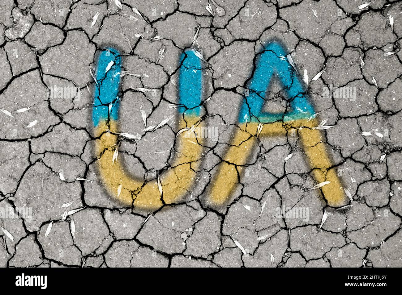 Ukraine national blue and yellow colors and inscription UA on a mud texture of dry cracks on the ground Stock Photo