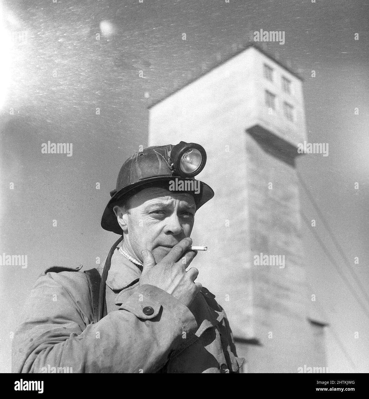 Kiruna Sweden in the 1950s. The open mine and a miner in front of the tower that the lift machinery for transportation of workers and machinery up and down the mine. Sweden 1954 Kristoffersson BP24-6 Stock Photo