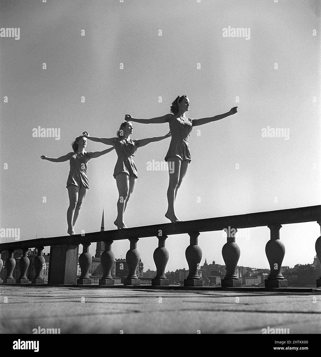 Gymnastics in the 1950s. Three young female gymnasts are standing on the wall outside Stockholm city hall. The three hold their arms legs and body in the same position. Sweden Photo Kristoffersson ref CZ67-9 Stock Photo