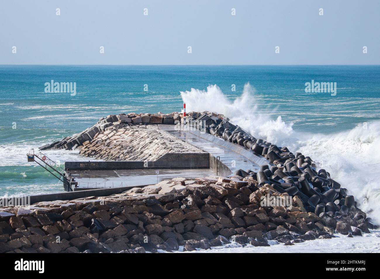 big ocean wave hit in a jetty from a pier in a stormy day Stock Photo
