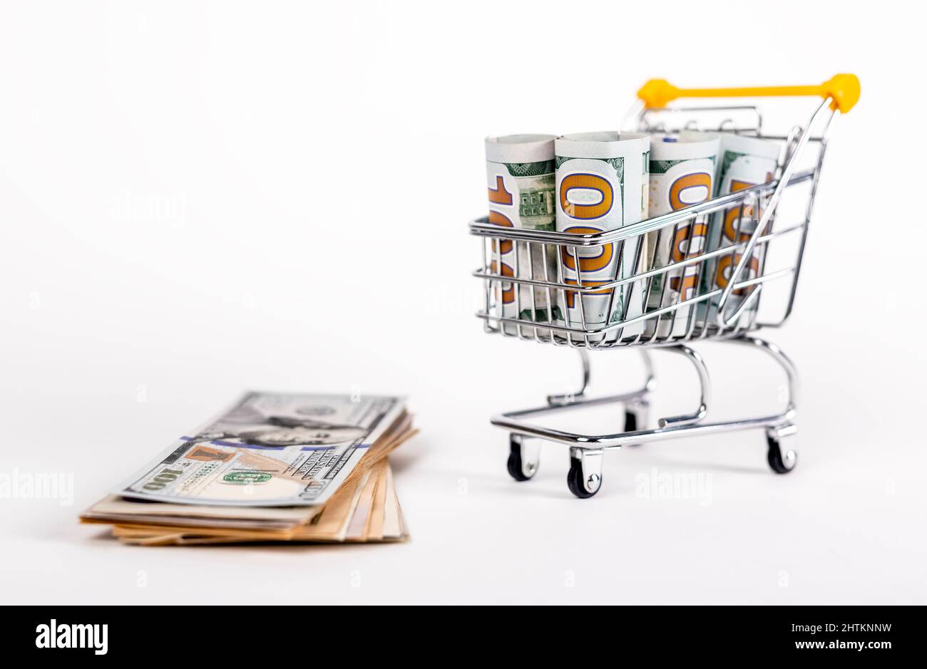 Trolley with rolled dollar bills and money stack. Income concept. Savings and money spent by shopping. High quality photo Stock Photo