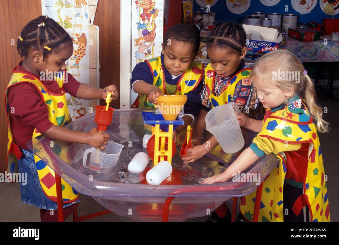 group of multiracial four year olds playing with water measurers at pre-school Stock Photo