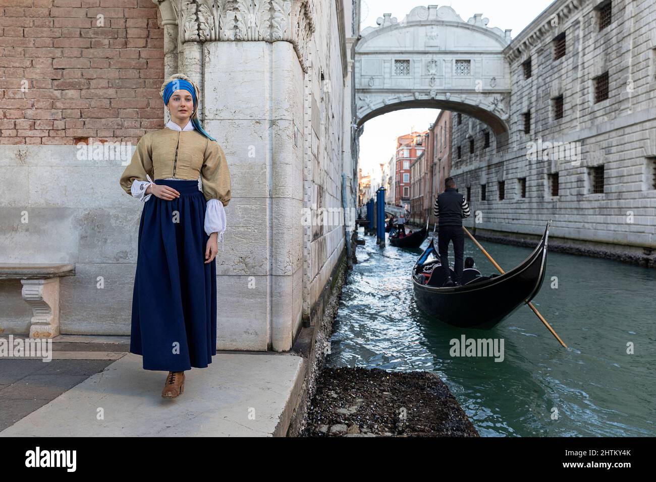 Woman in a beautiful traditional venetian costume and mask posing like Vermeer’s Girl With a Pearl Earring near Ponte della Paglia, Venice carneval Stock Photo