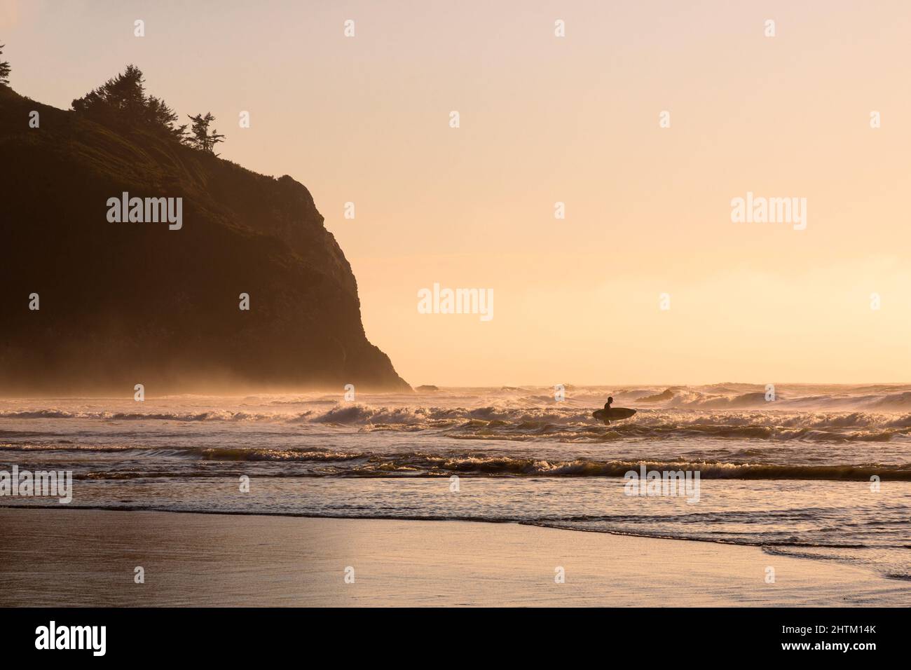Silhouette of this loan surfer in the waves near a cliff.  Photographed at Trinidad State Beach in Humboldt County, California, USA. Stock Photo