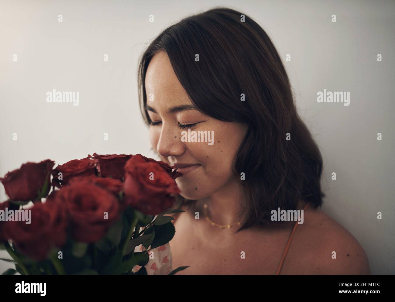 I dont have to wake up to smell the roses. Shot of a young woman smelling roses at home Stock