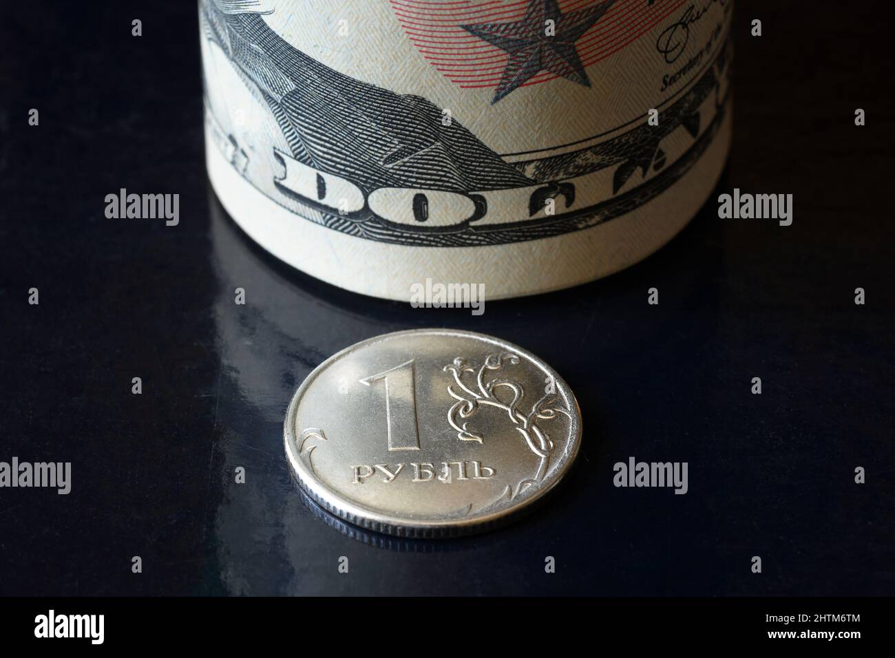 Russian ruble coin and dollar bills roll, ruble money is under pressure from geopolitics. Concept of ruble devaluation, inflation in Russia, economy f Stock Photo
