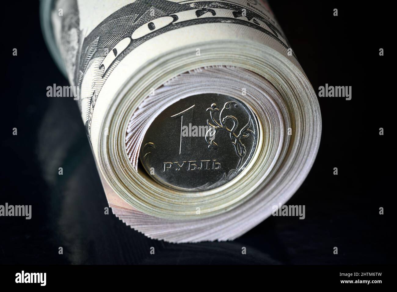 Russian ruble coin inside dollar bills roll, ruble money is under pressure from geopolitics. Concept of ruble devaluation, inflation in Russia, econom Stock Photo