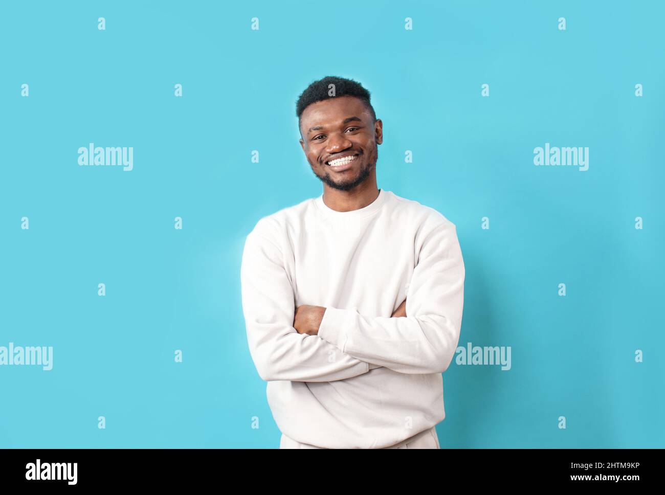 A young African-American man in a white T-shirt laughs on a blue isolated background Stock Photo
