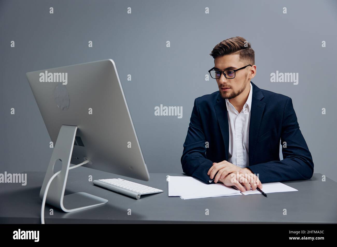 businessmen sitting at a desk in front of a computer Gray background ...