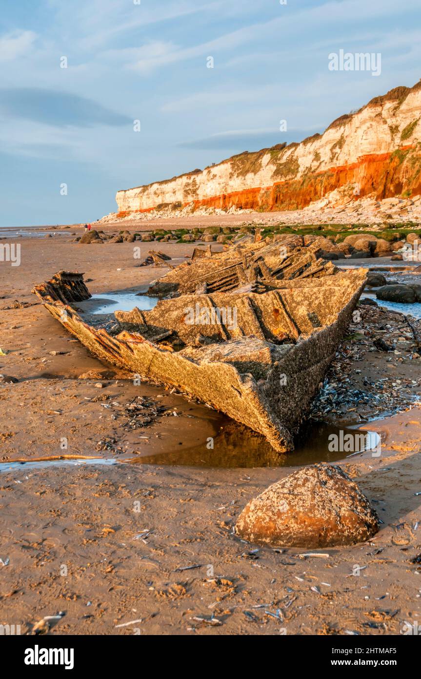 The wreck of the steam trawler Sheraton below the red & white striped cliffs of Hunstanton at low tide. Stock Photo