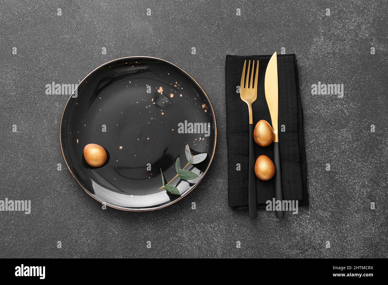 Table setting with Easter eggs and eucalyptus branch on dark background Stock Photo