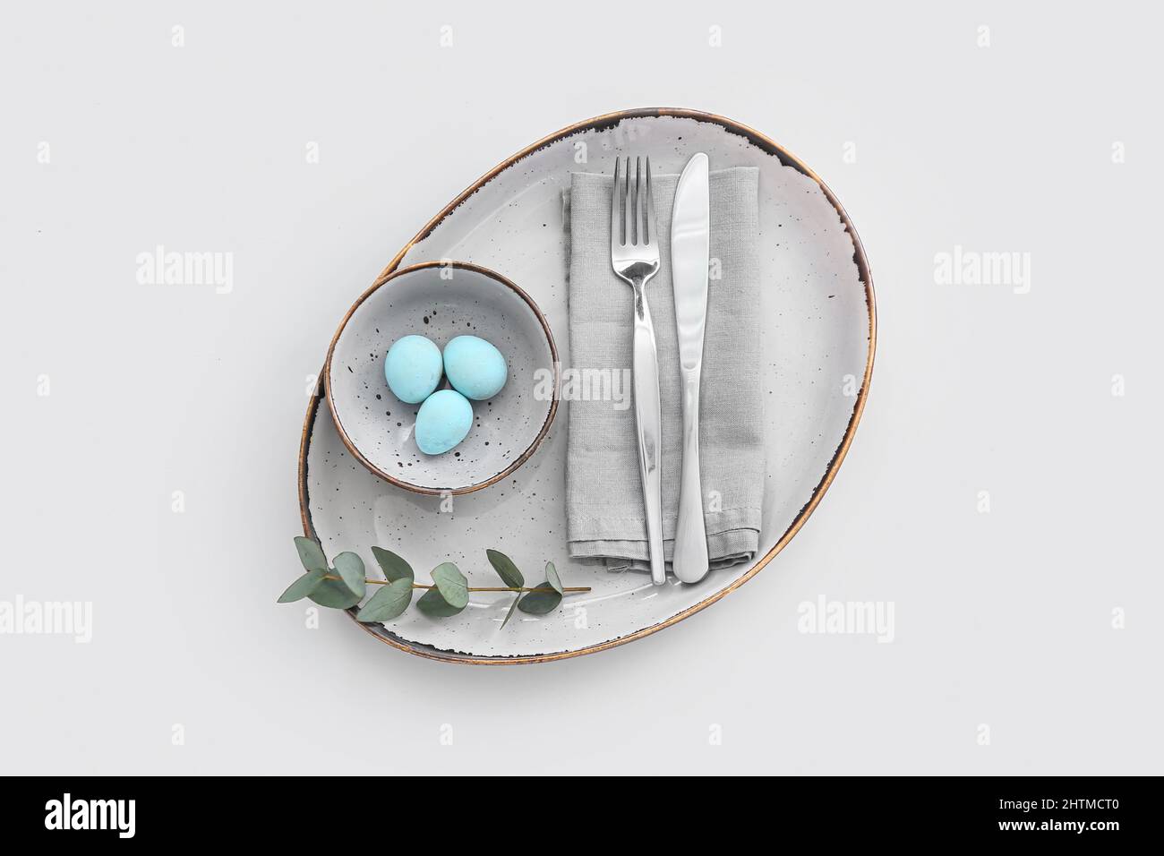 Table setting with Easter eggs and eucalyptus branch on white background Stock Photo