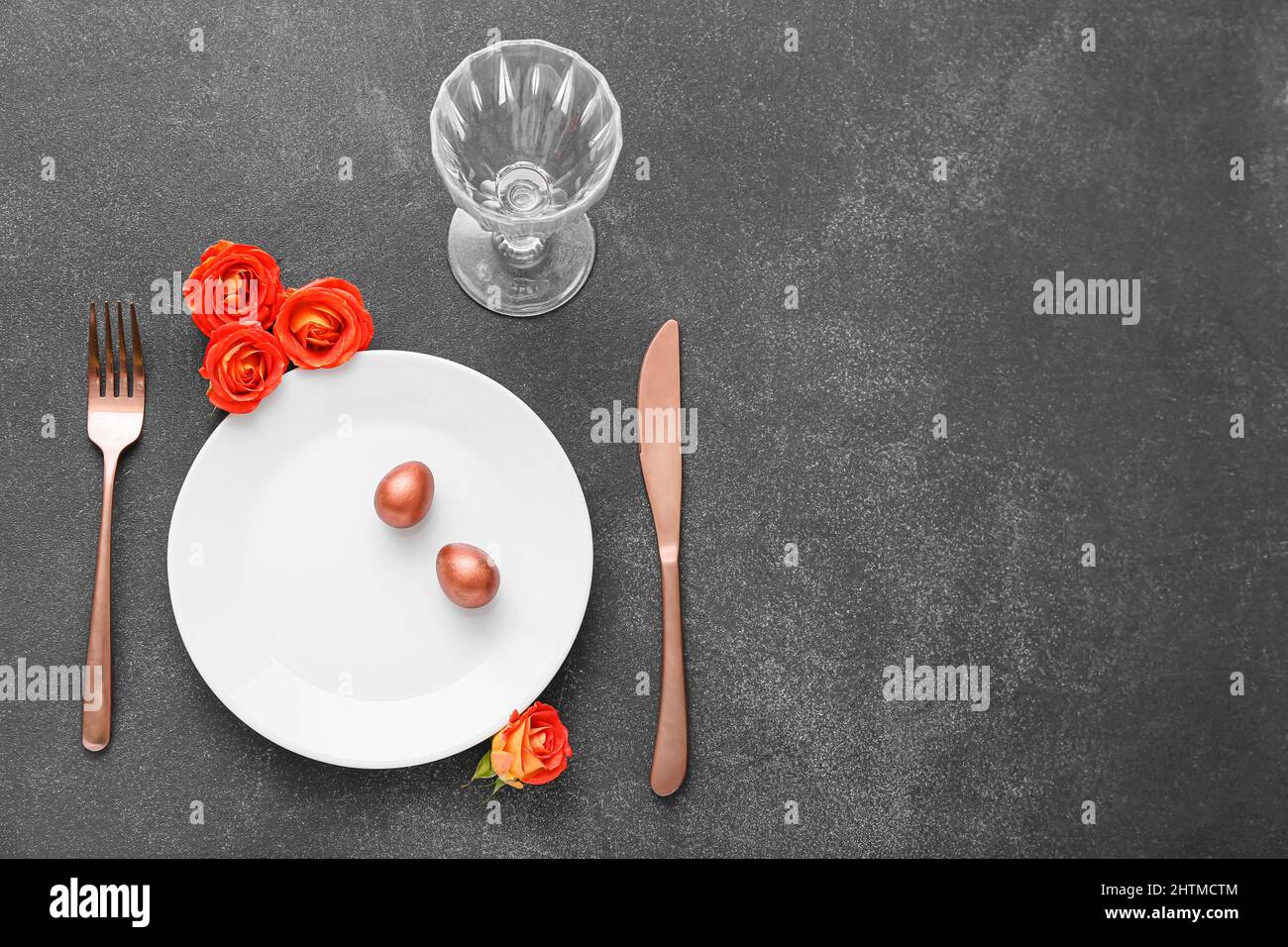 Table setting with Easter eggs and roses on dark background Stock Photo