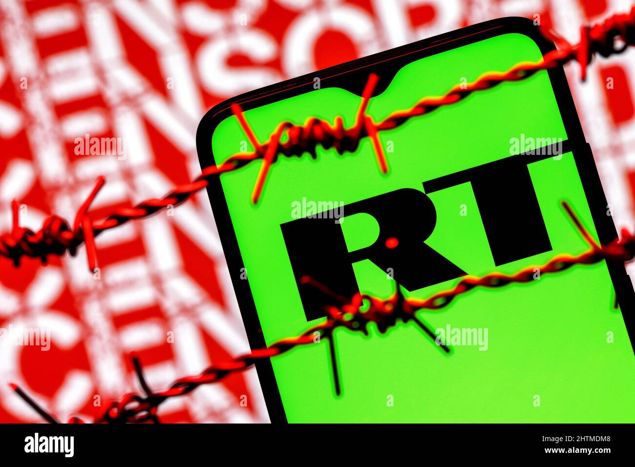 Smartphone with RT (Russia Today) logo on background of inscription censored behind barbed wire Stock Photo