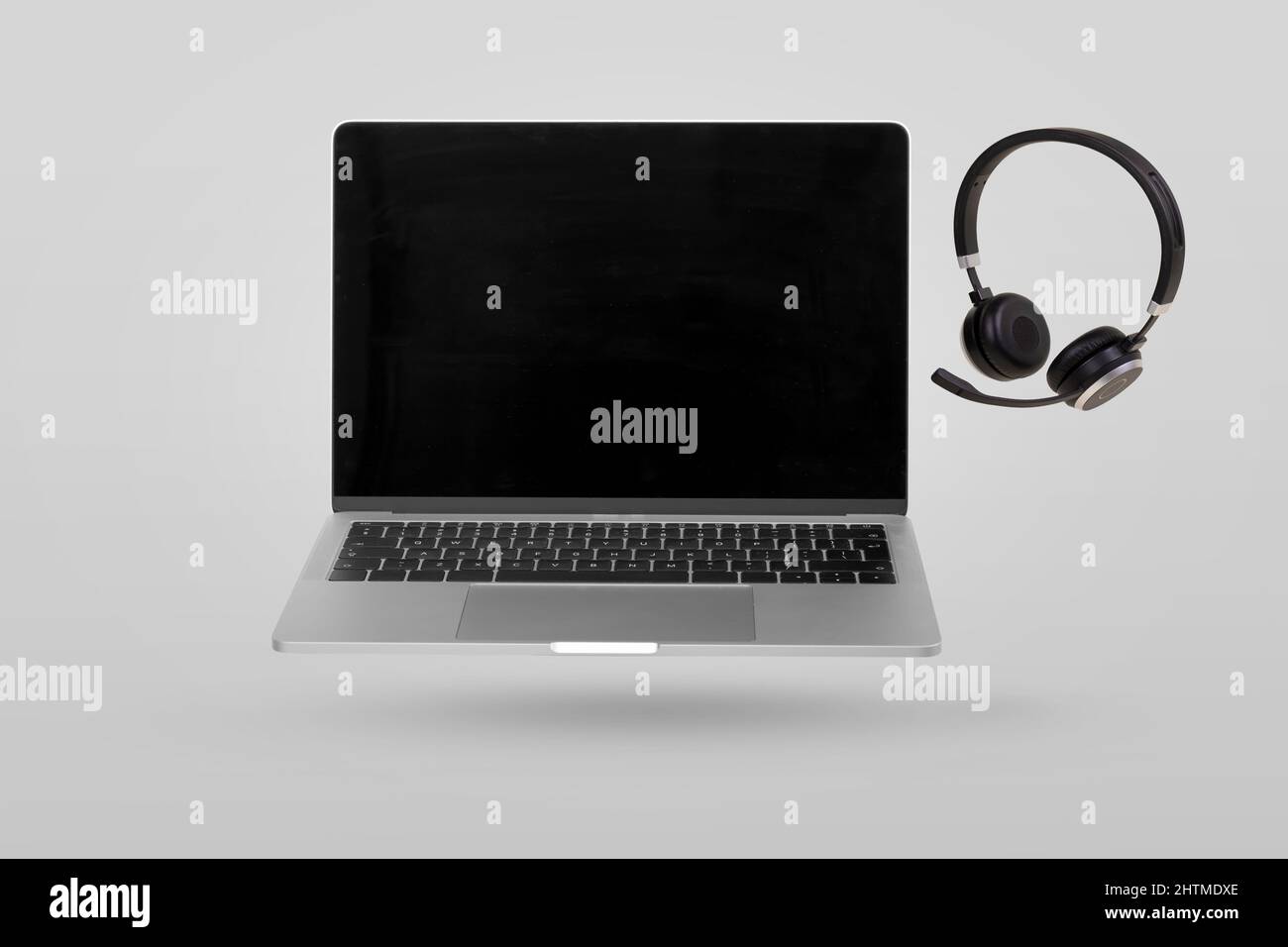 Laptop computer with empty screen and headset  levitating in the air on a gray background. Creative minimal background. Pop art, conceptual art. Suita Stock Photo