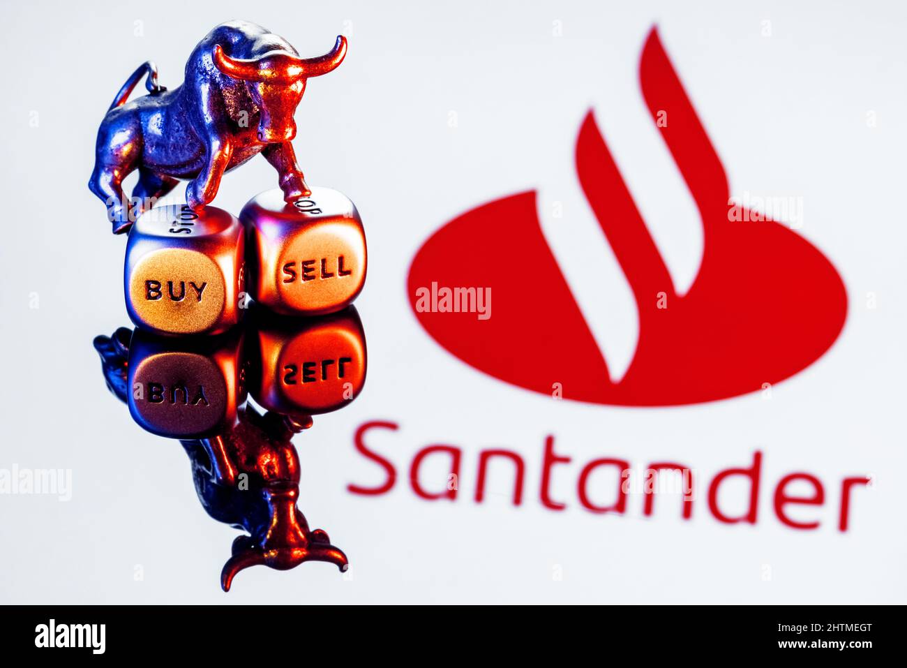 Metal bull stands on buy-sell dices on background of Santander bank logo Stock Photo