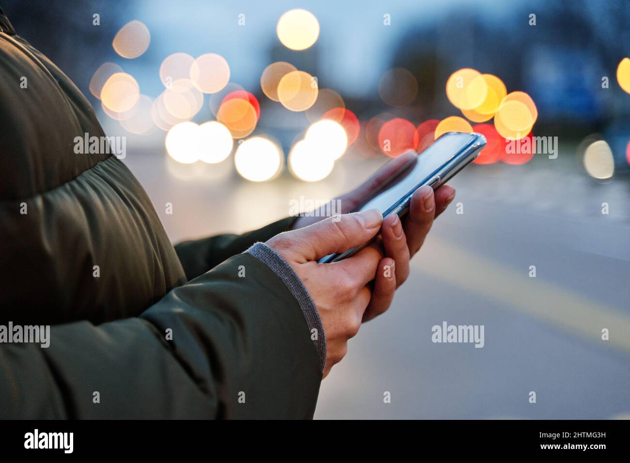 Close-up image of a woman's hands using smartphone at night on the city street, search or social networking concept, Stock Photo