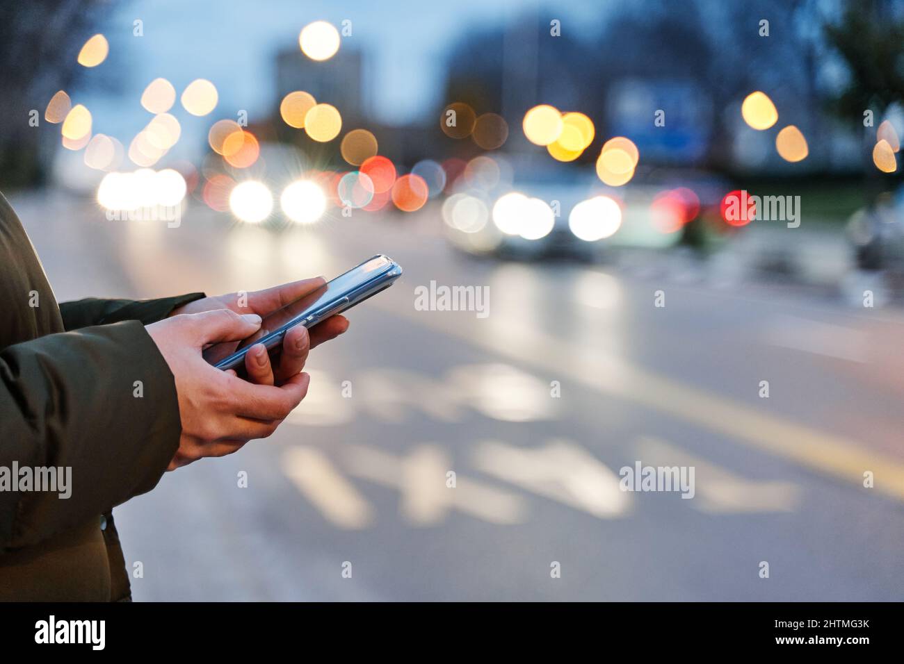 Close-up image of a woman's hands using smartphone at night on the city street, search or social networking concept, woman asking for transport via mo Stock Photo