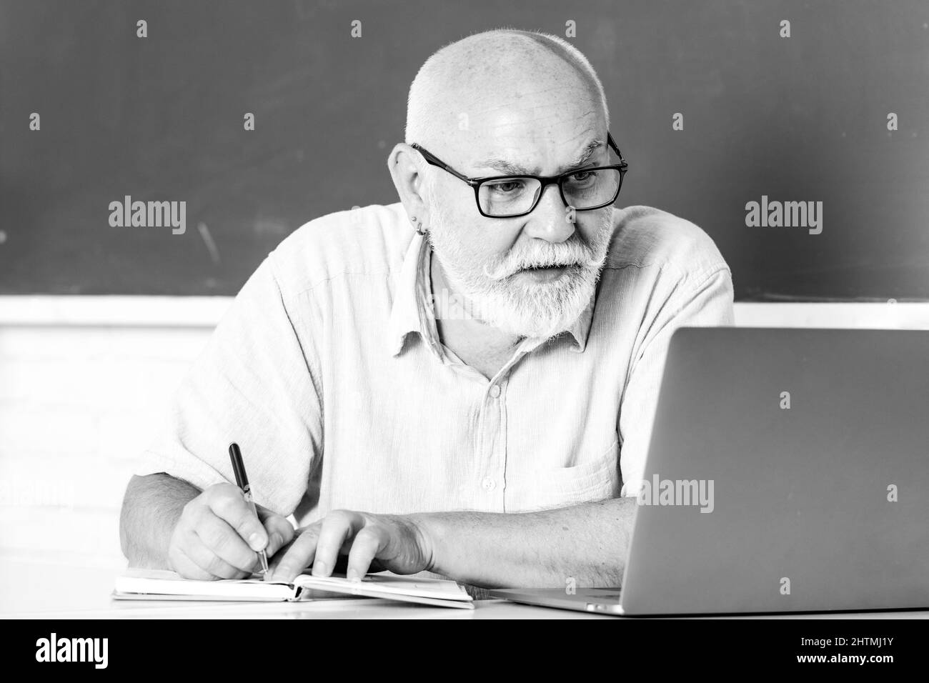 Elderly education and retired knowledge concept. Senior teacher teaching in the classroom on chalkboard. Teacher at university. Man senior teacher Stock Photo