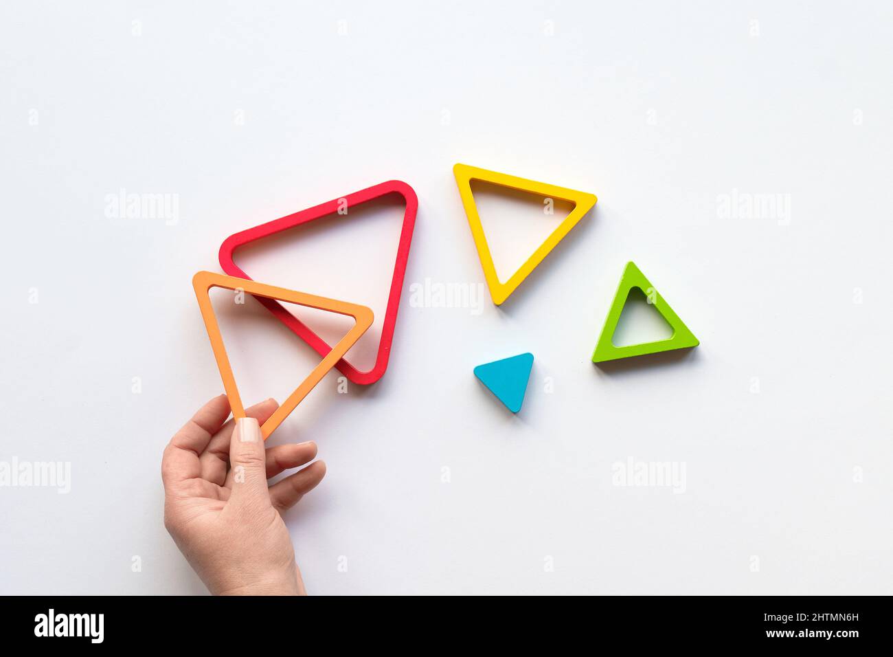 Hand with triangle. Nested wood triangles, concentric educational figures. Stacking puzzle. Stock Photo