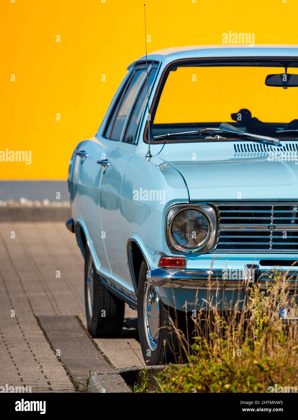 Sky blue retro car against a bright yellow wall. Color contrast