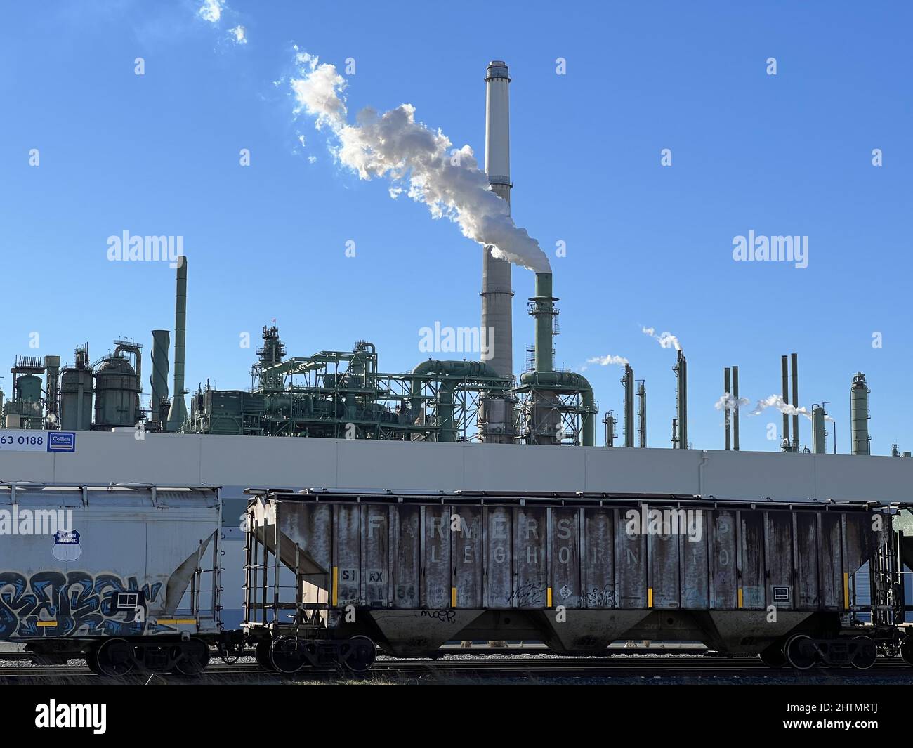 Smokestacks and machinery are visible at the Valero Refinery in Benicia, California, a refinery that processes crude oil, with freight train visible in foreground, February, 2022. Stock Photo