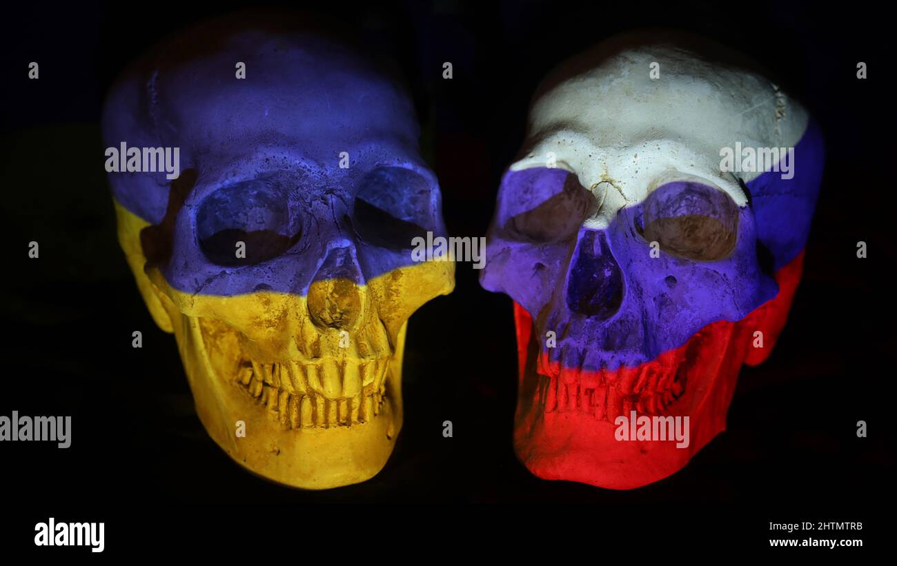 Russian and Ukrainian flags projected onto 2 human skulls against a plain black background. Human cost of war and the tension between the two sides Stock Photo