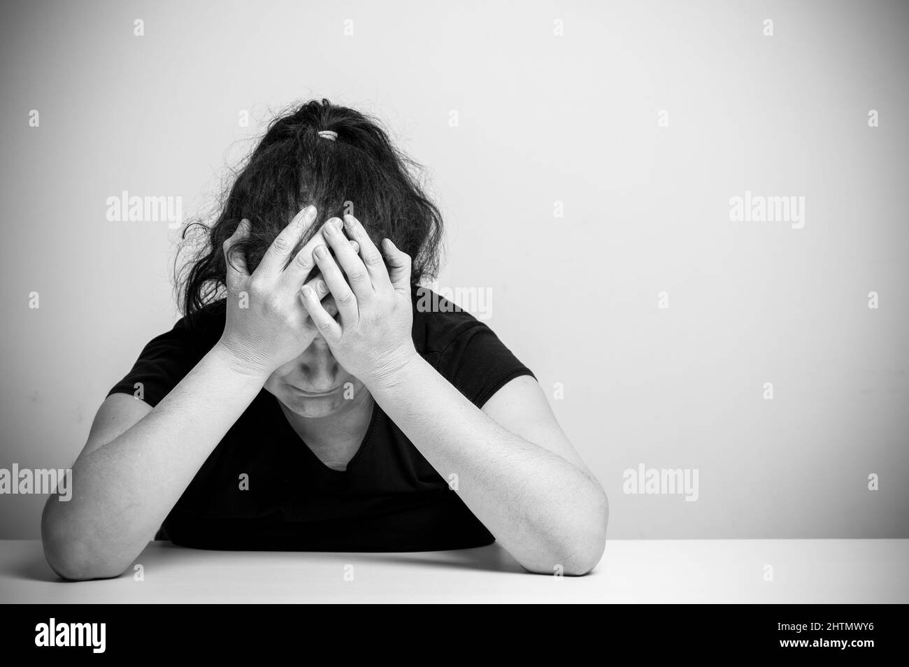 Homeless woman drug and alcohol addict sitting alone and depressed home feeling anxious and lonely, social documentary concept black and white Stock Photo