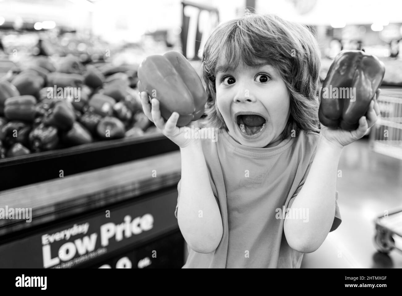 Happy little customer boy holdind trolley, shopping at supermarket, grocery store. Stock Photo