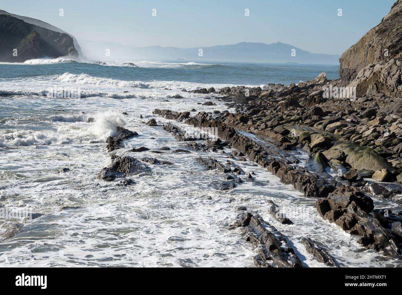 waves crashing over rock formation on cliff Stock Photo