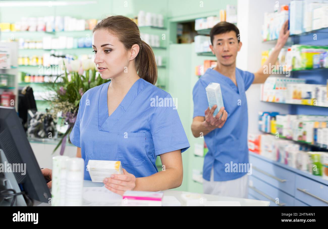 Positive pharmacist is standing near cashbox Stock Photo