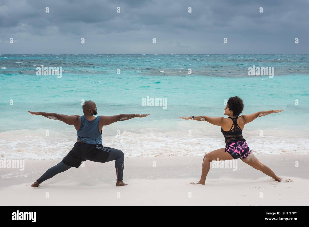 Couple practices yoga on Hope Town Bahamas beach. Stock Photo
