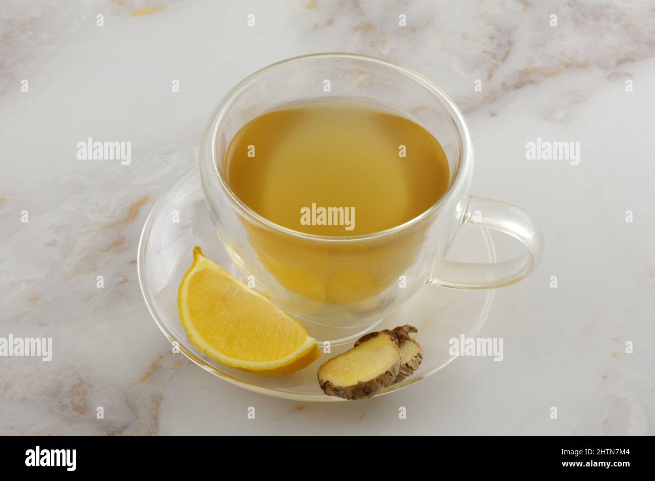 Ginger lemon tea with fresh lemon and ginger slices in insulated glass